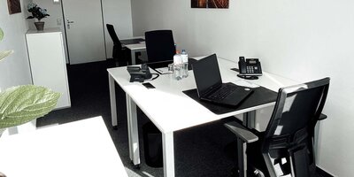 Innenansicht Büro mit zwei Arbeitsplätzen und Wandbild.