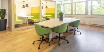 Büro-Lounge mit grünen Design-Sitzmöbeln und Holzakzenten.